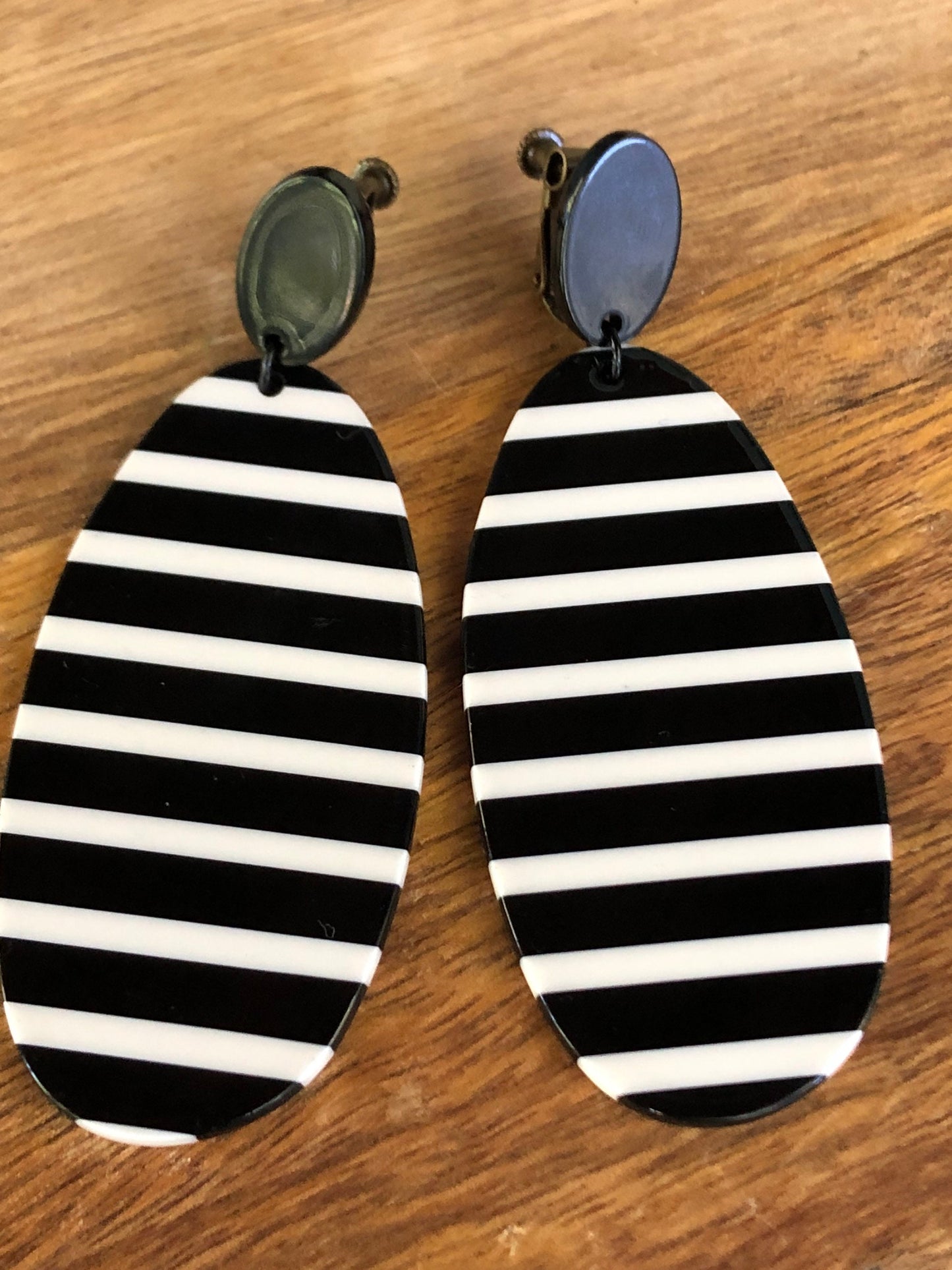 Oversized dangling black and white striped plastic oval clip on earrings