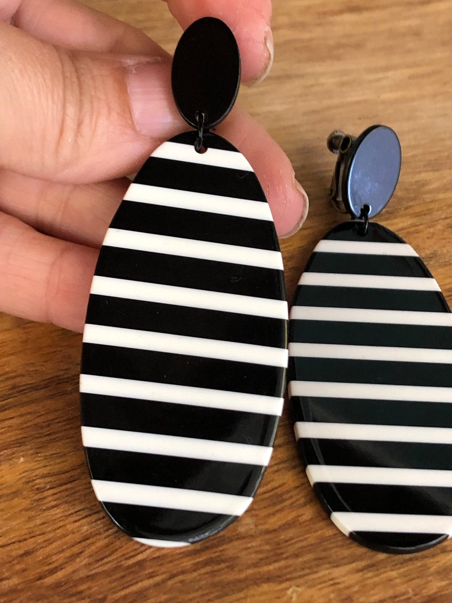 Oversized dangling black and white striped plastic oval clip on earrings