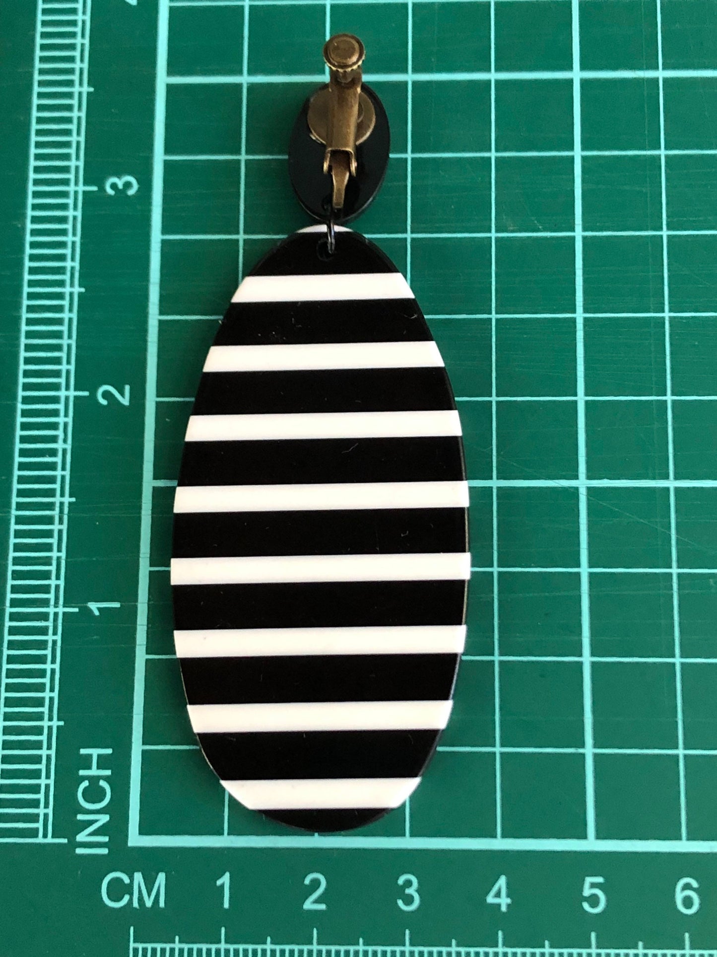 Oversized dangling black and white striped plastic oval clip on earrings