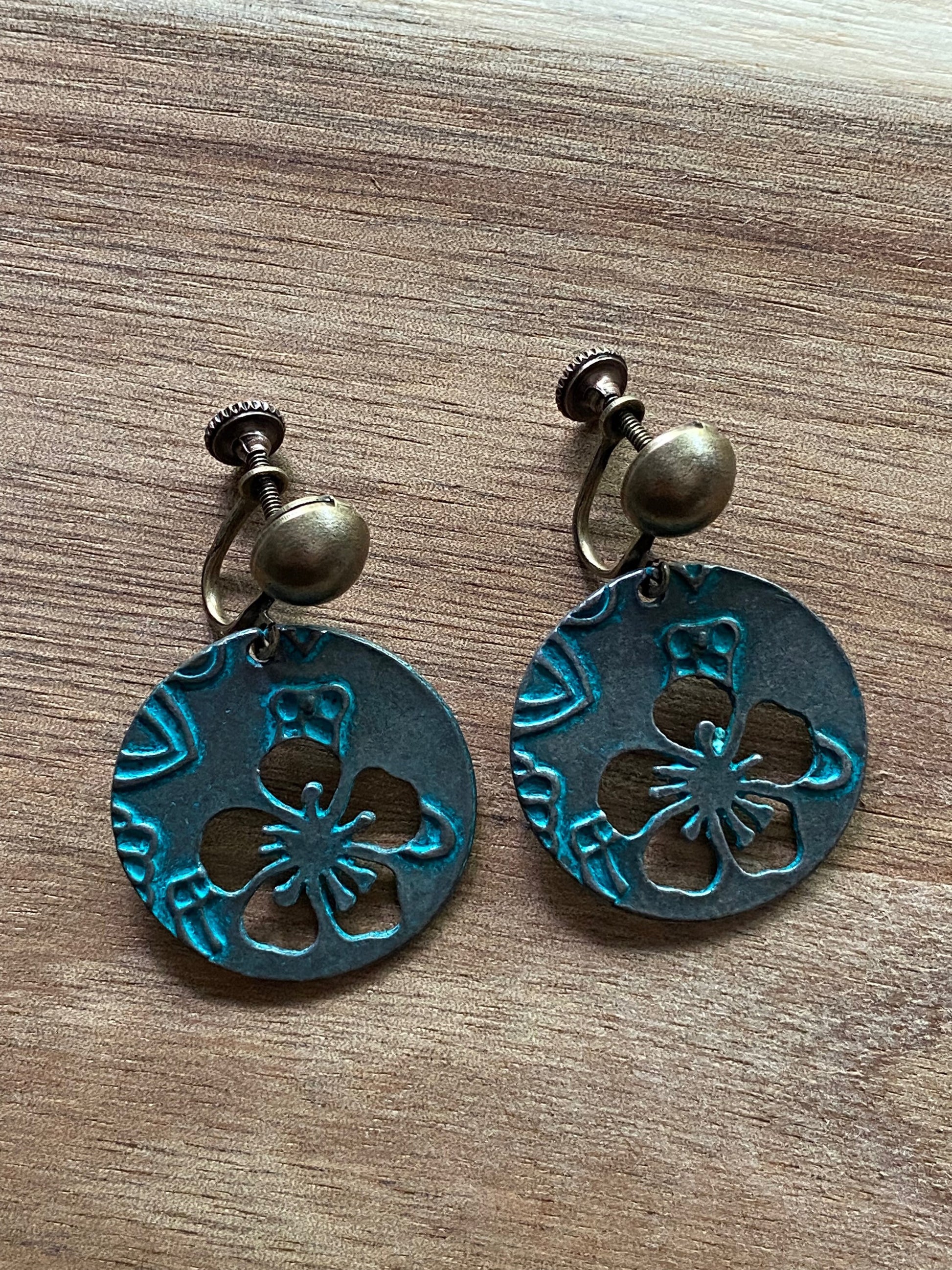 Danging bronze screwback dangling earrings with floral cutout design and turquoise patina for unpierced ears.