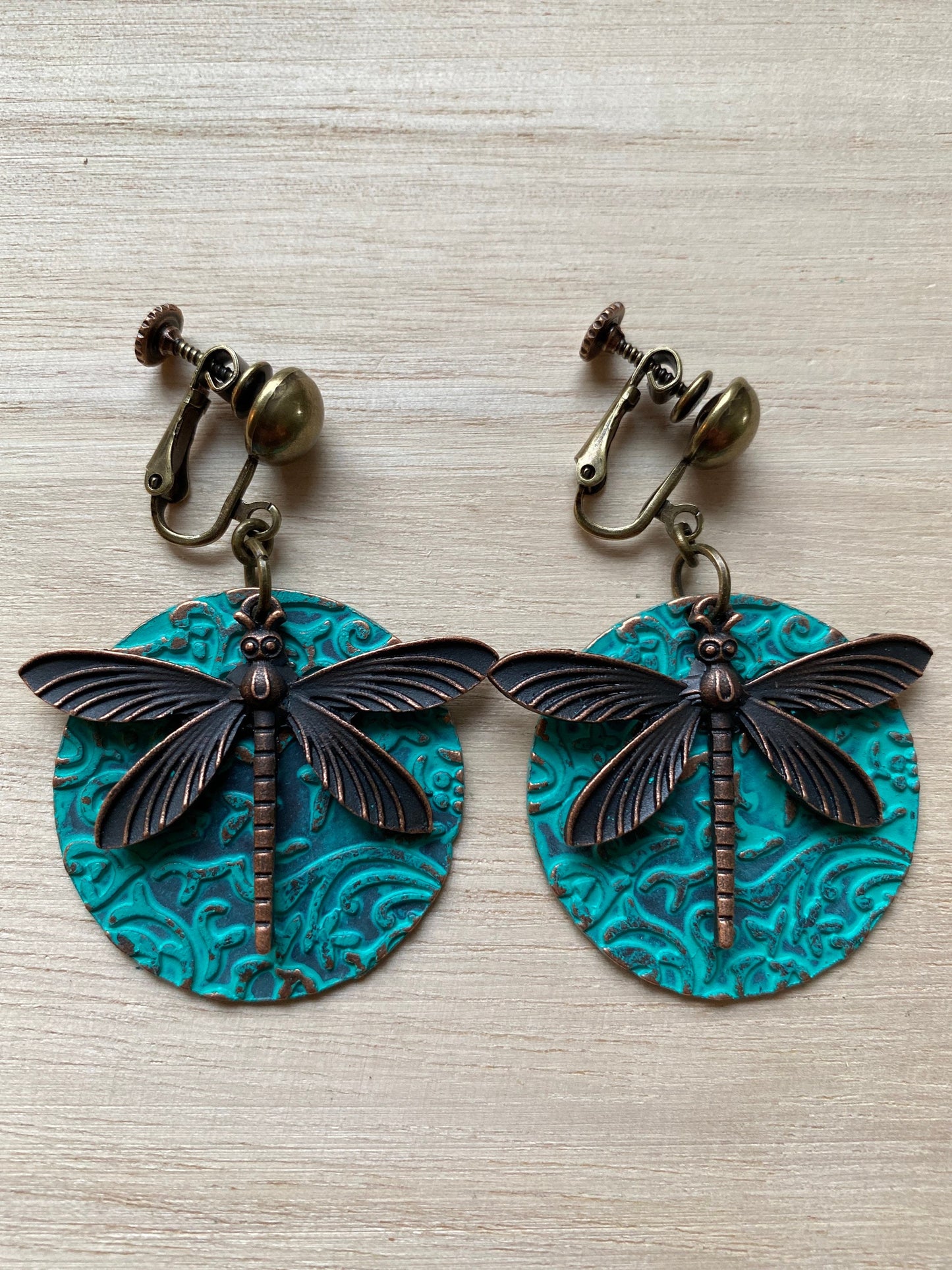 Dangling bronze and turqoise clip on earrings, bronze dragonfly pendant on turquoise medallion with hinged screwback closures for unpierced ears