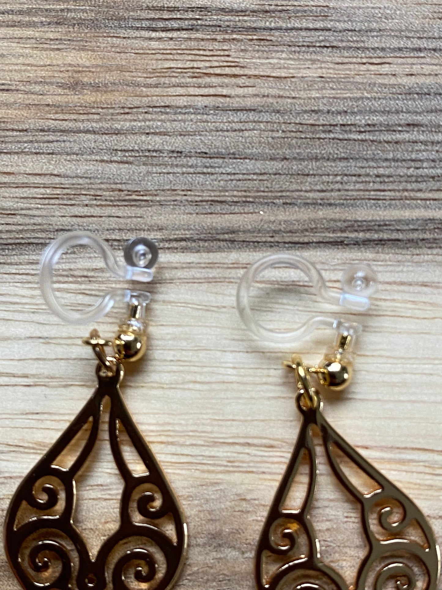 Dangling invisible clip on earrings with gold coloured cutout pendants