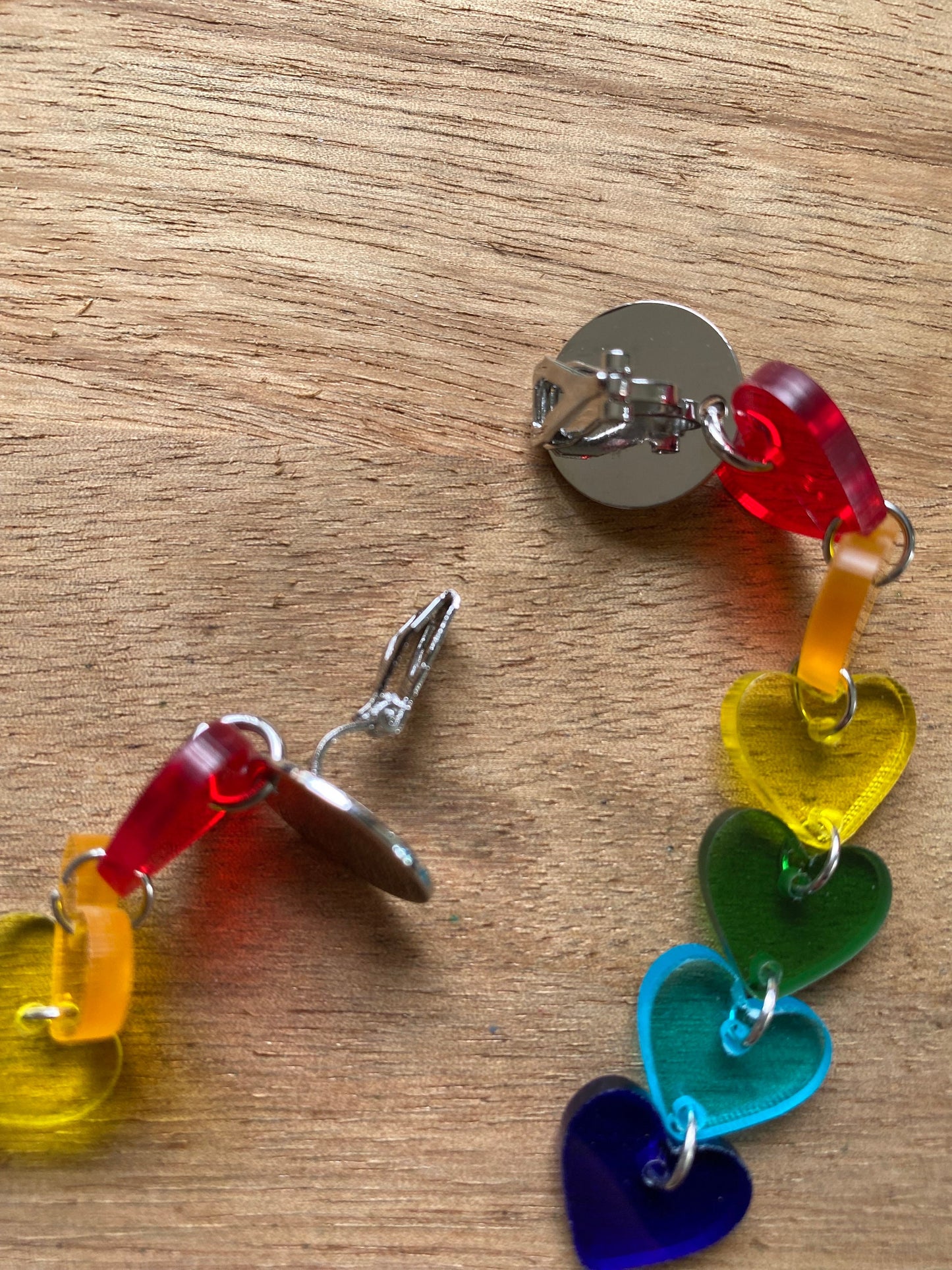 Dangling clip on clear rainbow heart earrings.