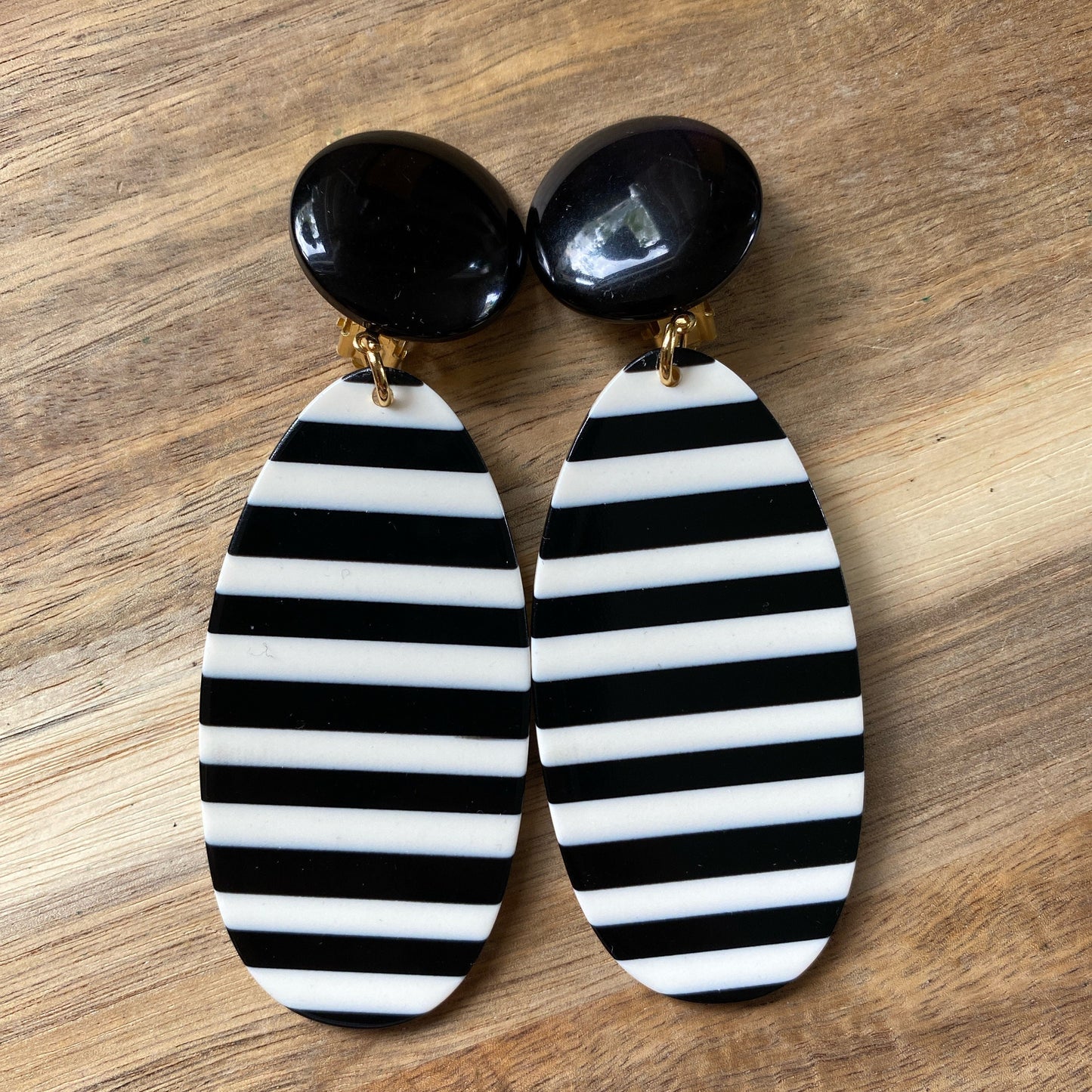 Oversized dangling black and white striped plastic oval clip on earrings