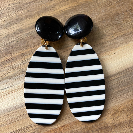 Oversized dangling black and white striped plastic oval clip on earrings